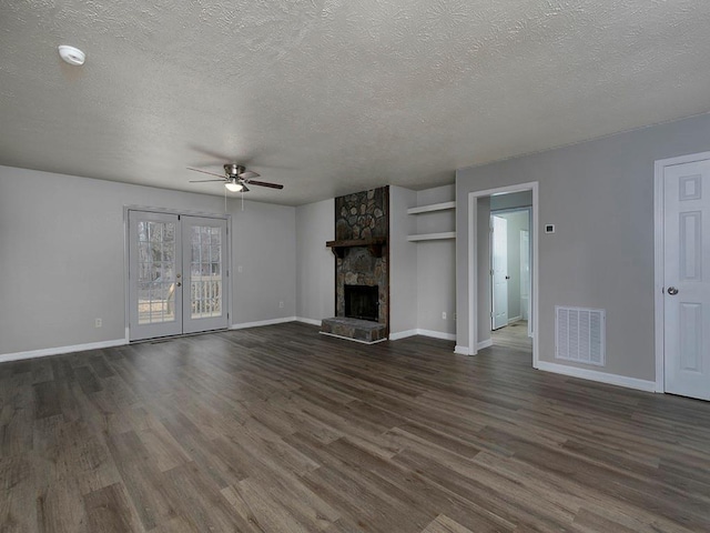 unfurnished living room featuring french doors, a fireplace, dark hardwood / wood-style flooring, and a textured ceiling