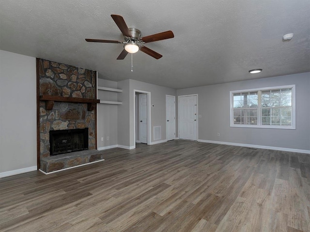 unfurnished living room with ceiling fan, hardwood / wood-style flooring, a fireplace, and a textured ceiling