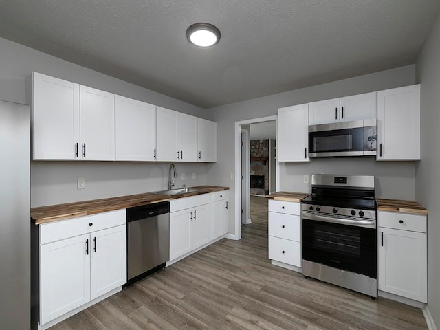 kitchen featuring white cabinetry, butcher block countertops, and appliances with stainless steel finishes