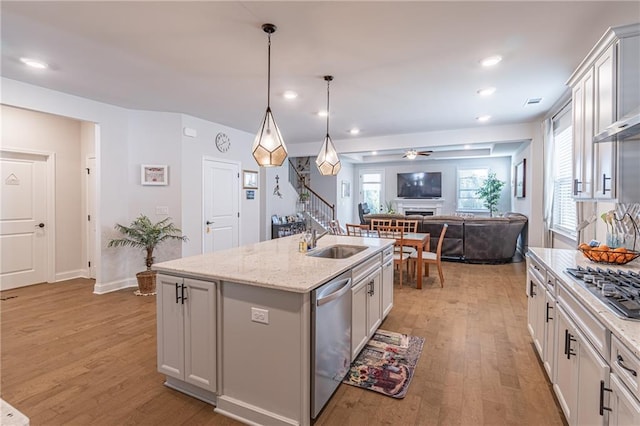 kitchen with sink, a kitchen island with sink, white cabinets, and light hardwood / wood-style flooring