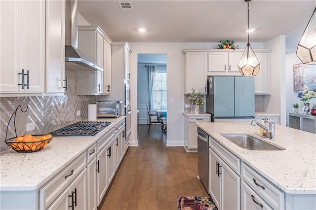 kitchen with dark wood-type flooring, sink, wall chimney range hood, hanging light fixtures, and appliances with stainless steel finishes