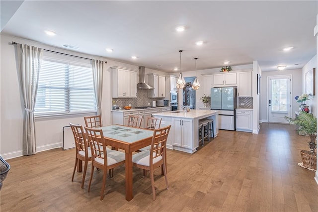 dining space featuring plenty of natural light, sink, and light hardwood / wood-style floors