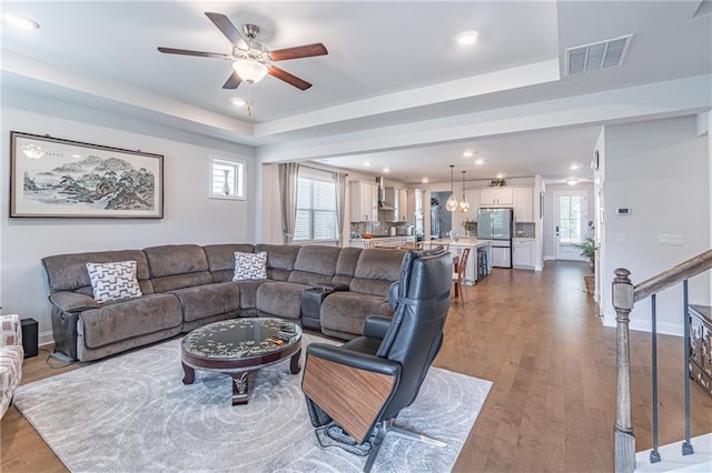 living room featuring hardwood / wood-style flooring, a healthy amount of sunlight, ceiling fan, and a tray ceiling