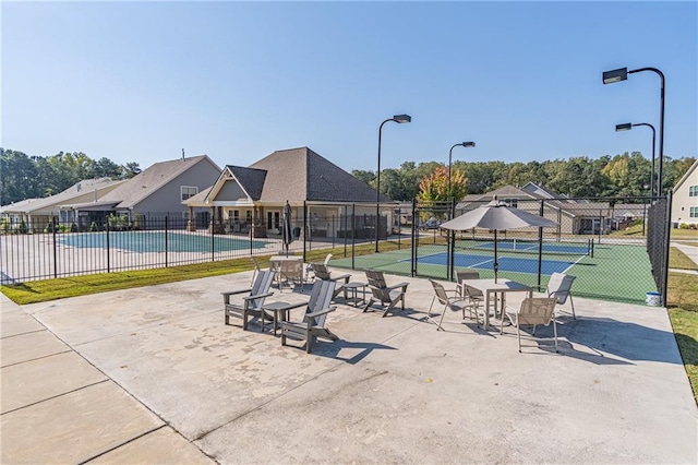 view of swimming pool featuring a patio area and tennis court