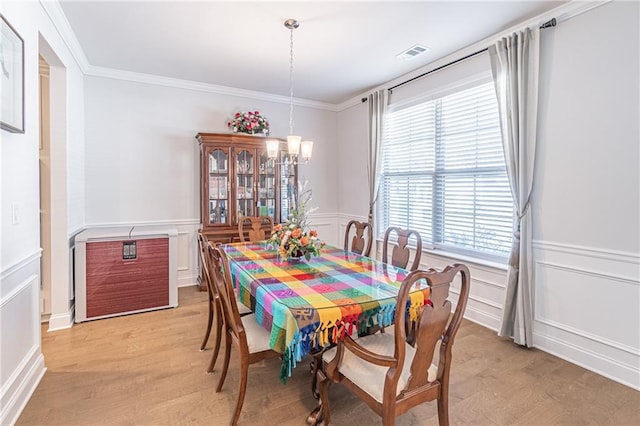 dining area with light hardwood / wood-style floors, crown molding, and a chandelier