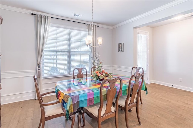 dining area featuring ornamental molding, an inviting chandelier, and light wood-type flooring