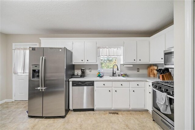 kitchen with white cabinets, sink, stainless steel appliances, and a textured ceiling