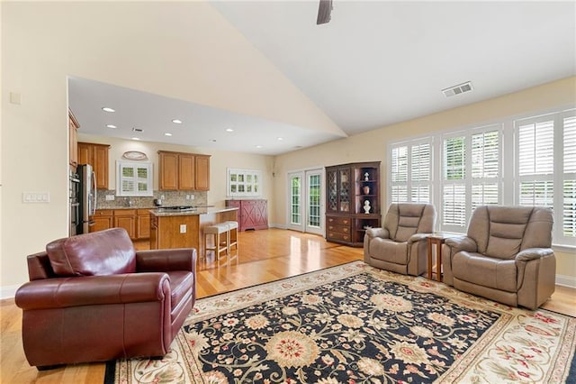 living area with light wood-style floors, lofted ceiling, baseboards, and recessed lighting