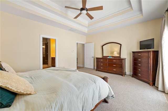 bedroom with light carpet, crown molding, a tray ceiling, baseboards, and ensuite bath