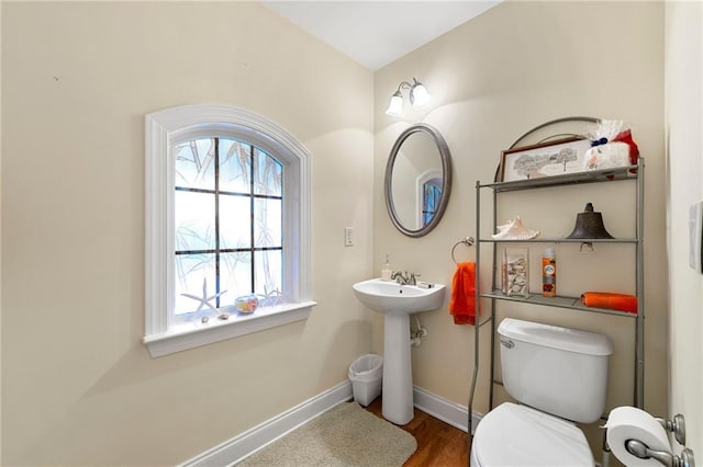 half bathroom featuring baseboards, wood finished floors, and toilet