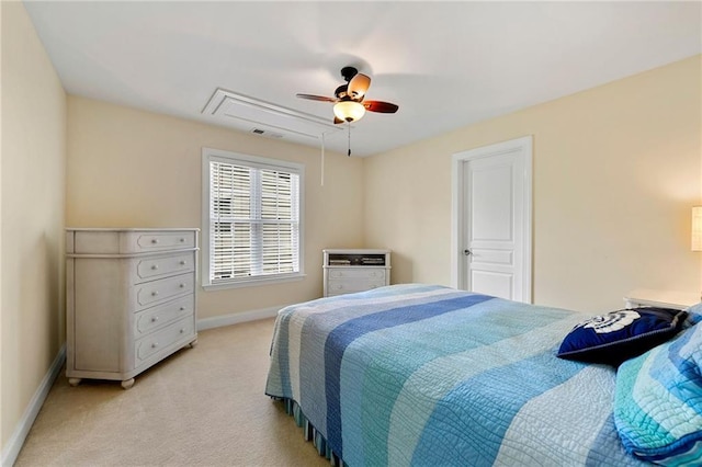 bedroom featuring attic access, baseboards, light colored carpet, and a ceiling fan
