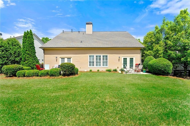 rear view of property with a chimney, a patio, and a yard