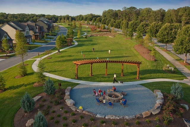 surrounding community featuring an outdoor fire pit and a lawn