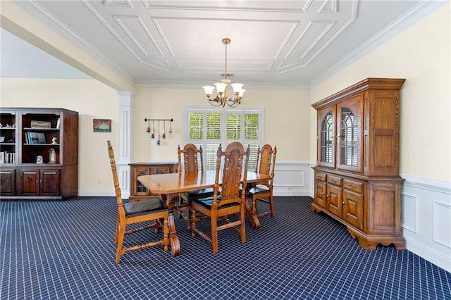 dining area featuring dark carpet, a chandelier, a wainscoted wall, crown molding, and a decorative wall