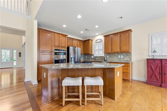kitchen featuring appliances with stainless steel finishes, light wood-type flooring, a center island, backsplash, and recessed lighting