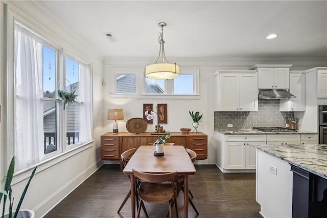 kitchen featuring light stone counters, hanging light fixtures, dark hardwood / wood-style flooring, and white cabinets