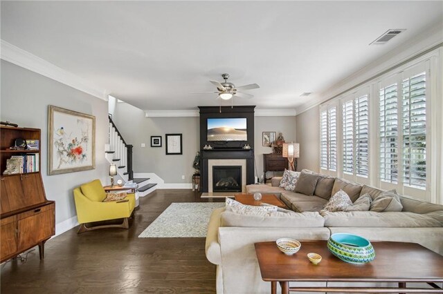 living room featuring ornamental molding, ceiling fan, a fireplace, and dark hardwood / wood-style flooring