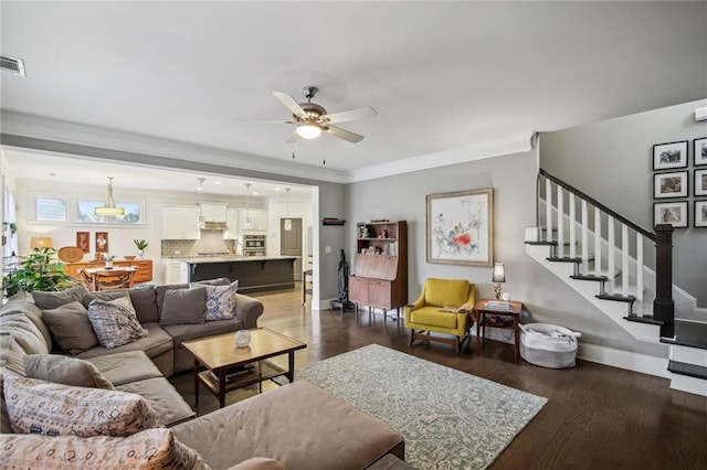 living room featuring crown molding, dark hardwood / wood-style floors, and ceiling fan with notable chandelier