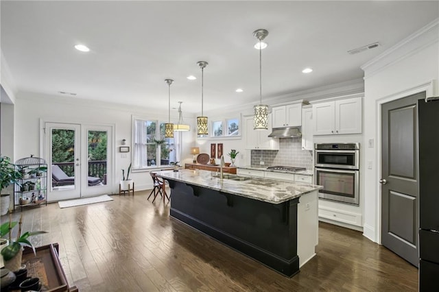 kitchen featuring a breakfast bar area, dark hardwood / wood-style flooring, white cabinetry, a kitchen island with sink, and light stone countertops