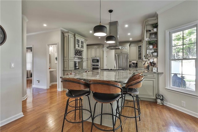 kitchen featuring a center island, pendant lighting, appliances with stainless steel finishes, island range hood, and light stone counters