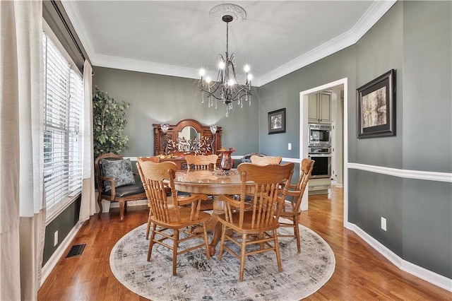 dining area featuring a chandelier, ornamental molding, and wood-type flooring