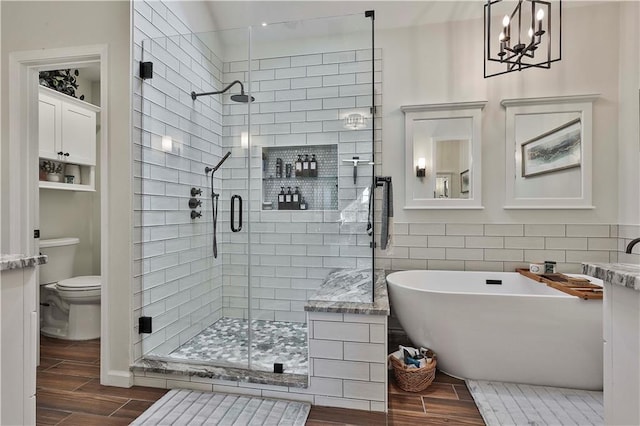 bathroom featuring toilet, an inviting chandelier, and plus walk in shower