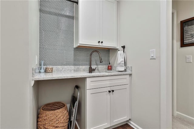 kitchen featuring decorative backsplash, white cabinets, and sink