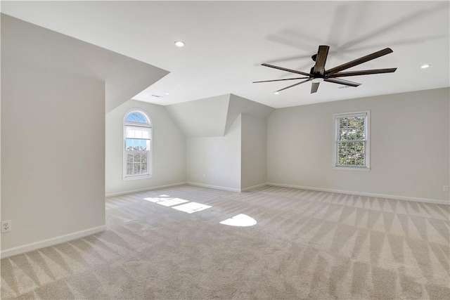 additional living space featuring vaulted ceiling, ceiling fan, a healthy amount of sunlight, and light colored carpet