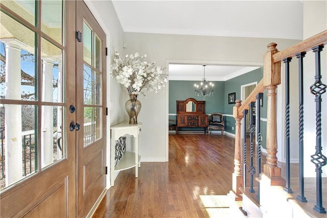 foyer with a chandelier, dark wood-type flooring, a wealth of natural light, and ornamental molding