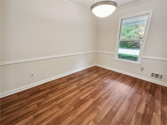 spare room with hardwood / wood-style floors and crown molding