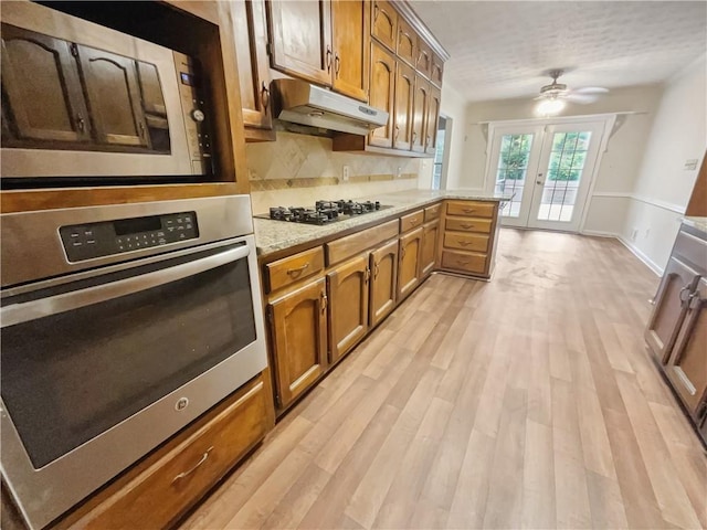 kitchen with french doors, stainless steel appliances, light hardwood / wood-style floors, decorative backsplash, and ceiling fan