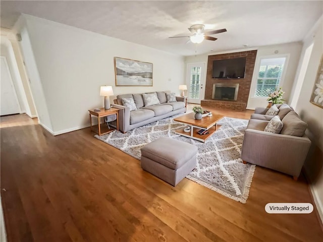 living room featuring hardwood / wood-style floors, ceiling fan, and a fireplace