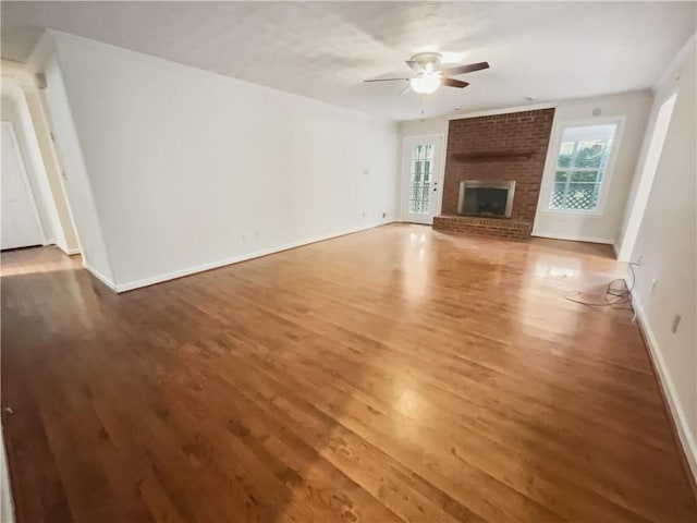 unfurnished living room featuring hardwood / wood-style flooring, ceiling fan, and a fireplace