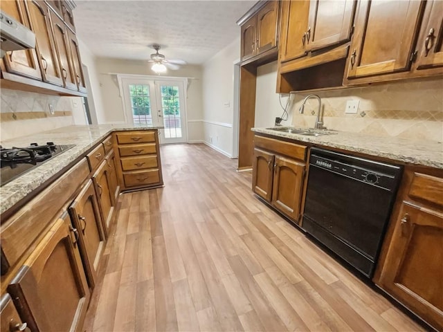 kitchen featuring decorative backsplash, light hardwood / wood-style flooring, black appliances, and range hood