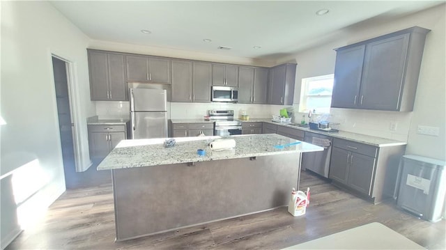 kitchen with appliances with stainless steel finishes, a kitchen island, light wood-style floors, and gray cabinetry