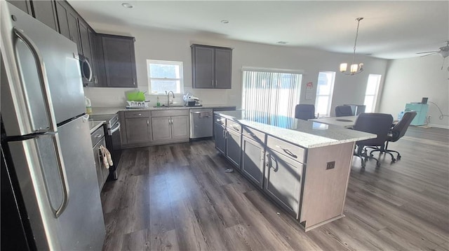 kitchen featuring appliances with stainless steel finishes, pendant lighting, dark wood-style flooring, and a center island