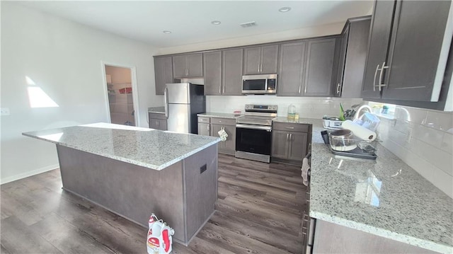 kitchen with a center island, dark wood finished floors, visible vents, decorative backsplash, and appliances with stainless steel finishes