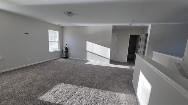 carpeted empty room featuring attic access and baseboards