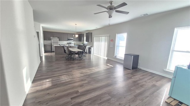 dining room featuring baseboards, visible vents, dark wood finished floors, and a ceiling fan