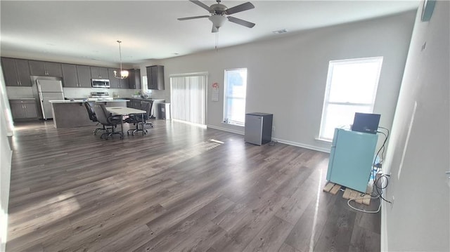 interior space with dark wood-style floors, ceiling fan, visible vents, and baseboards