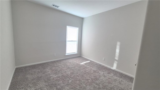 spare room featuring carpet floors, visible vents, and baseboards