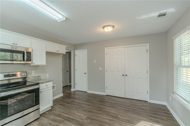 kitchen with white cabinetry, a textured ceiling, hardwood / wood-style flooring, stainless steel appliances, and light stone countertops