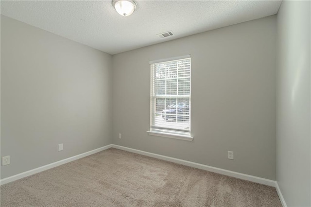 spare room featuring light carpet and a textured ceiling