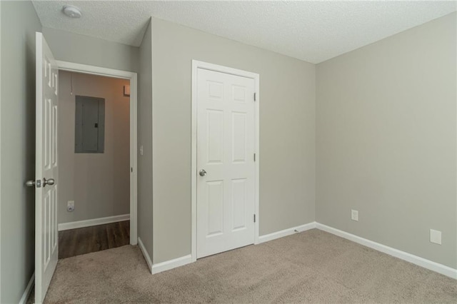 unfurnished bedroom featuring electric panel, carpet floors, and a textured ceiling