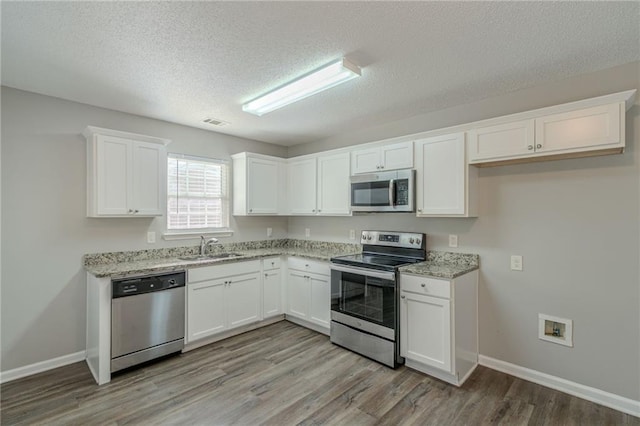 kitchen with white cabinetry, sink, light hardwood / wood-style flooring, and stainless steel appliances