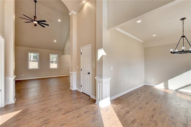 unfurnished living room with recessed lighting, wood finished floors, high vaulted ceiling, baseboards, and ceiling fan with notable chandelier