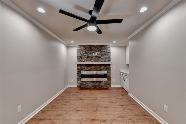 unfurnished living room with crown molding, light wood-type flooring, a fireplace, and baseboards