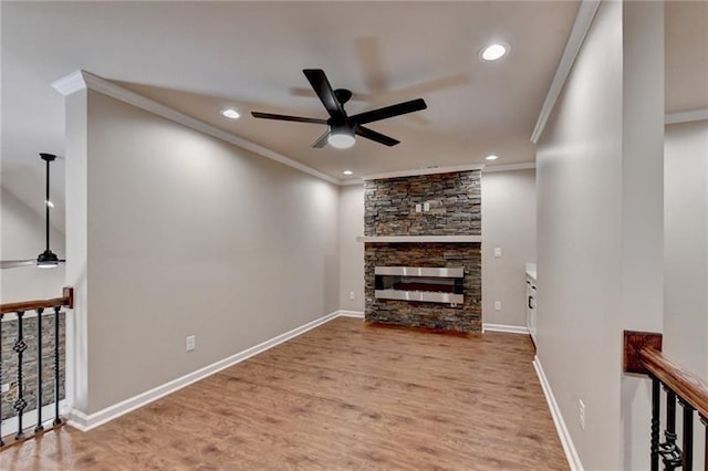 living area featuring light wood-type flooring, a fireplace, baseboards, and crown molding