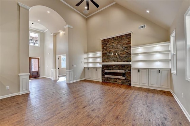 unfurnished living room with ceiling fan with notable chandelier, high vaulted ceiling, ornamental molding, and wood finished floors