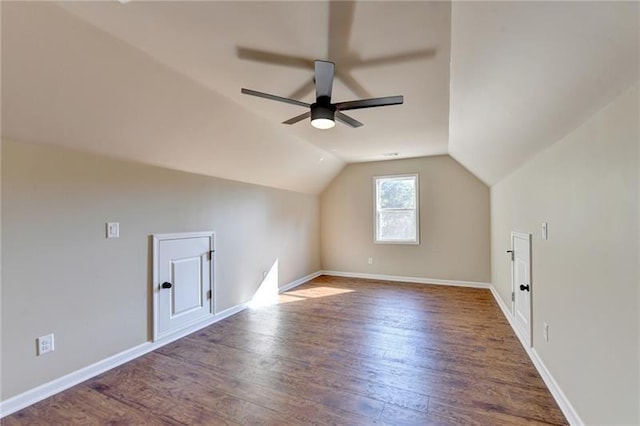 additional living space featuring dark wood-style floors, vaulted ceiling, a ceiling fan, and baseboards